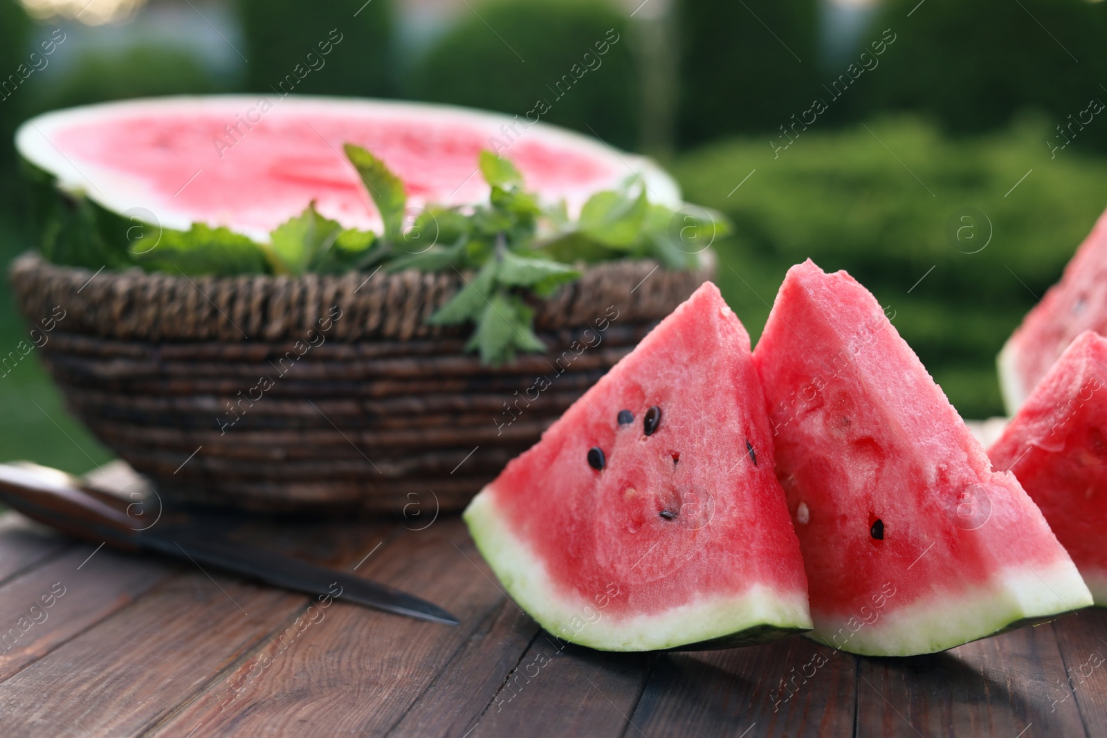 Photo of Tasty ripe watermelon on wooden table outdoors, closeup. Space for text
