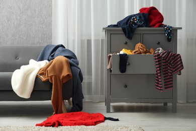 Photo of Room and dresser cluttered with clothes. Messy house