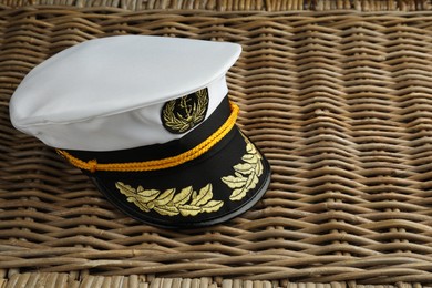 Photo of Peaked cap with accessories on wicker surface, space for text