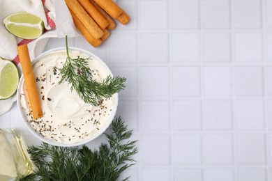 Delicious cream cheese with grissini stick and ingredients on white tiled table, flat lay. Space for text