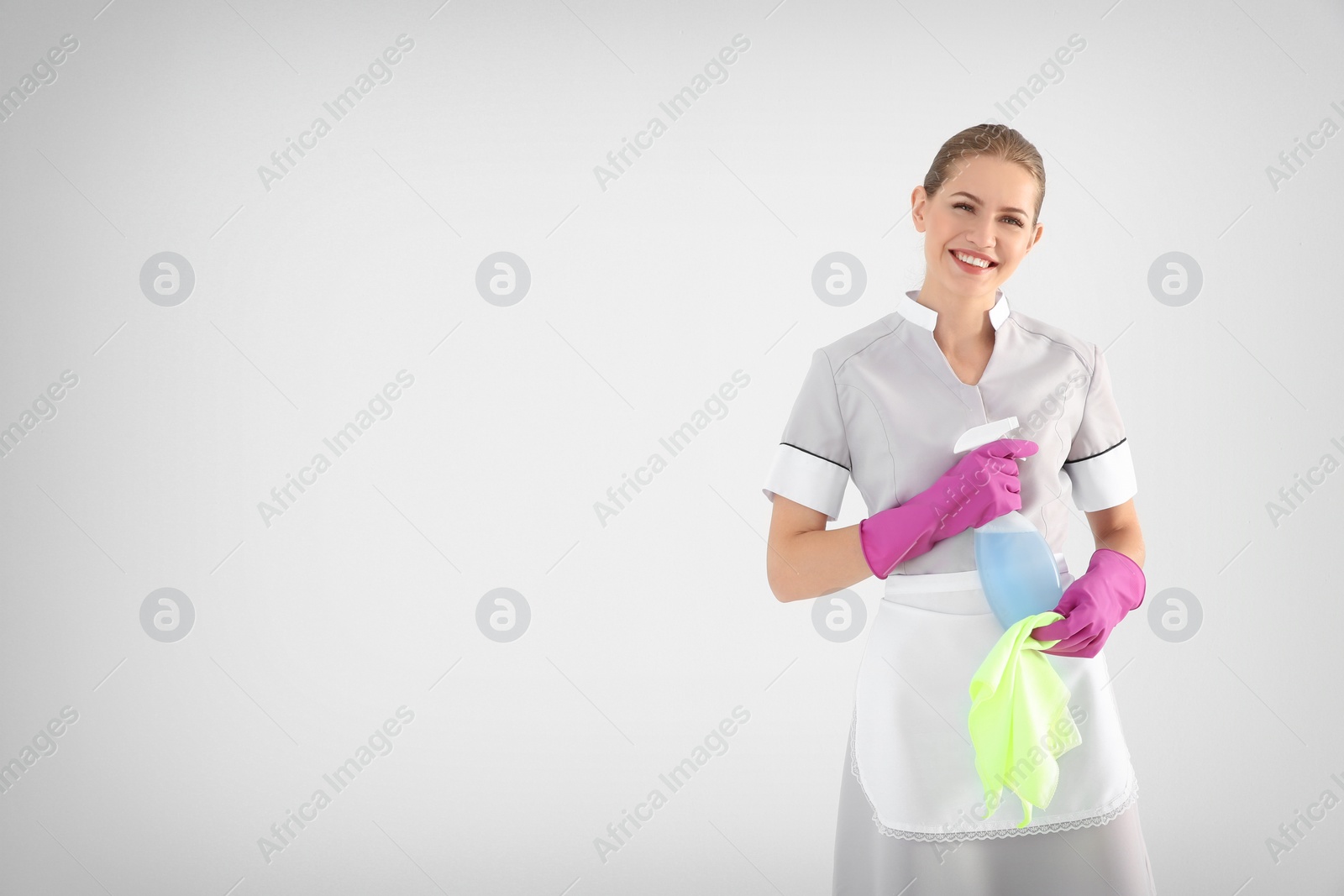 Photo of Young chambermaid with rag and detergent on white background