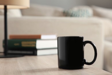 Photo of Black mug on wooden table indoors. Mockup for design