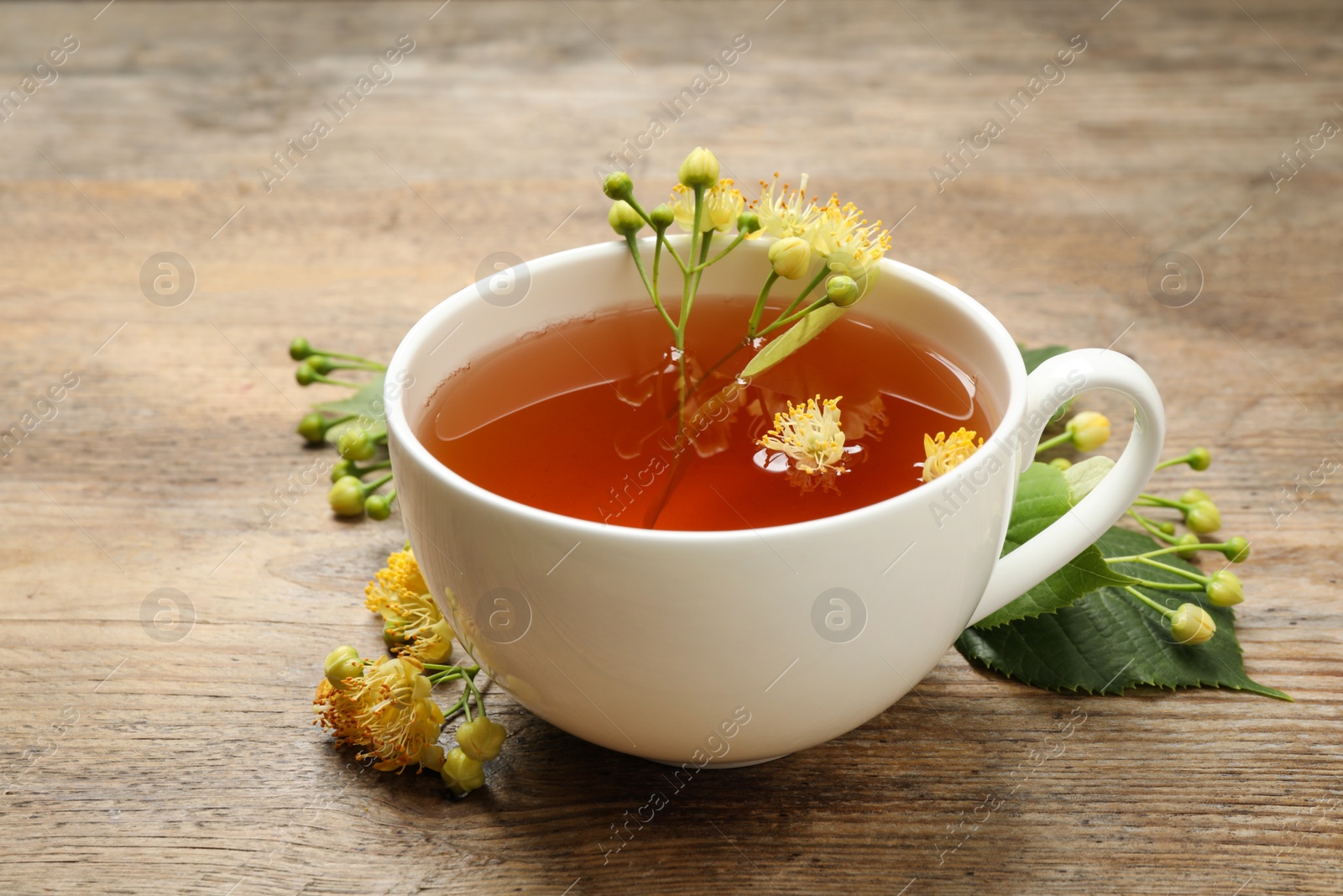 Photo of Cup of tea and linden blossom on wooden table