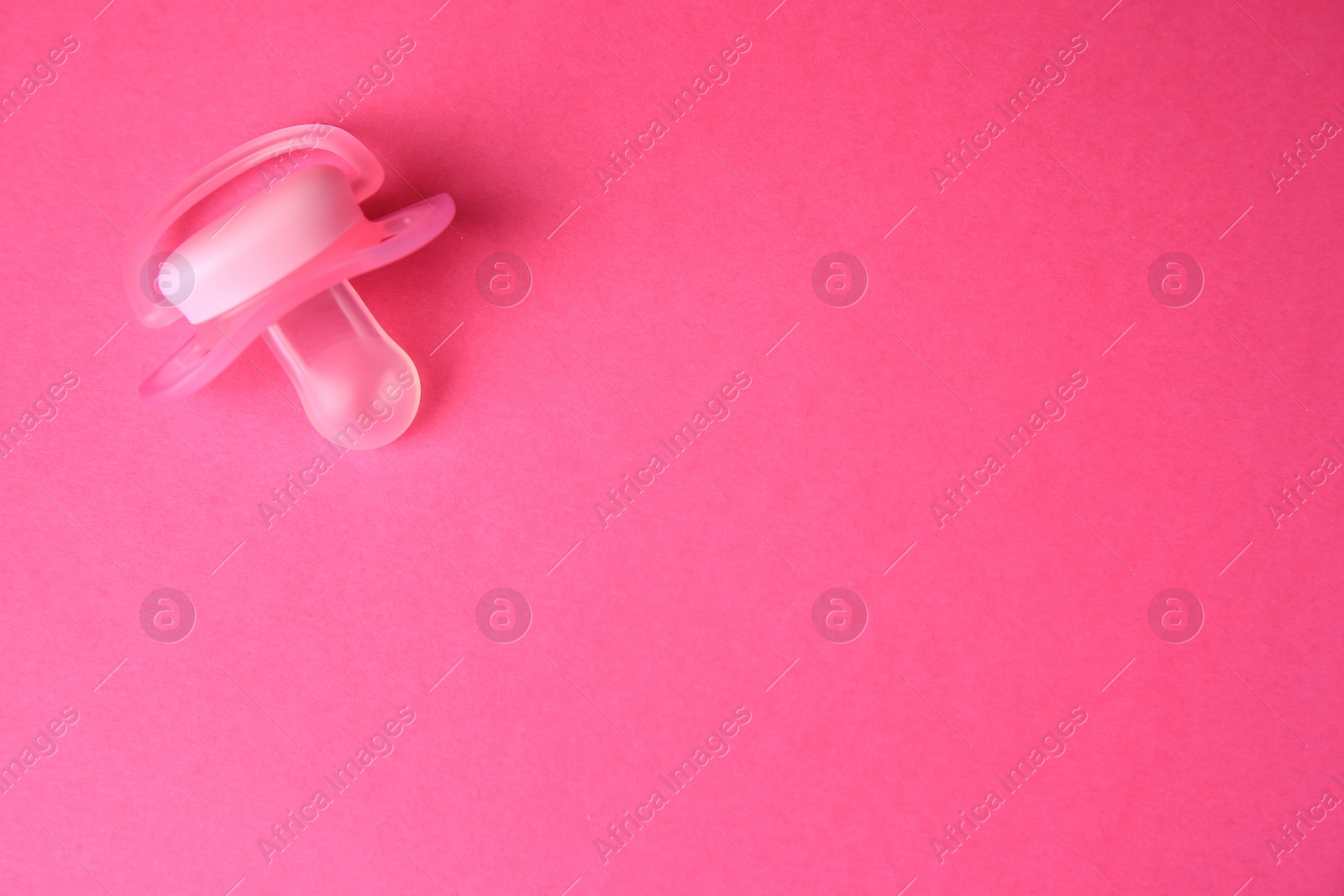 Photo of One baby pacifier on pink background, top view. Space for text