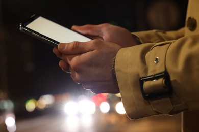 Man using smartphone on night city street, closeup