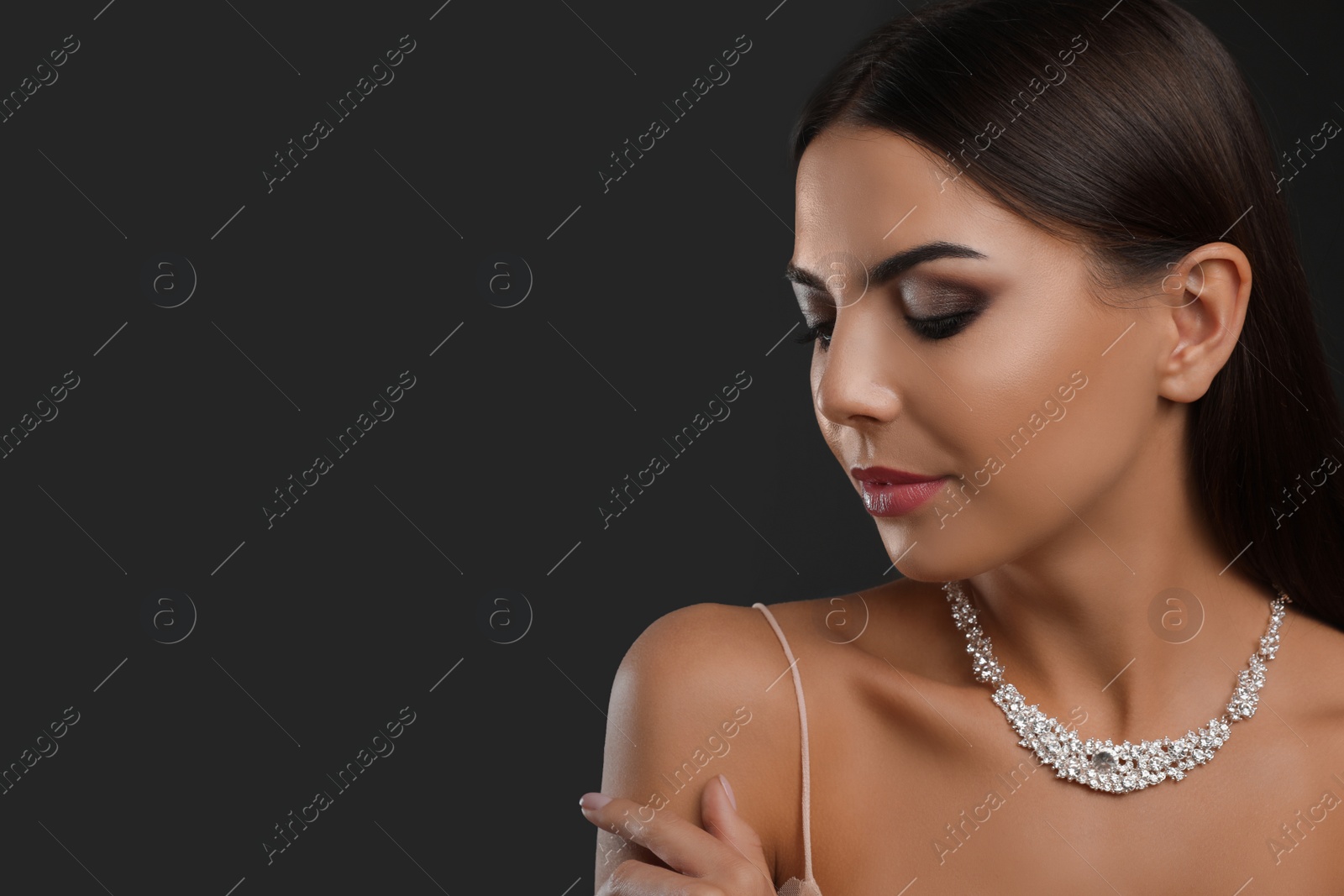 Photo of Beautiful young woman with elegant jewelry on dark background. Space for text