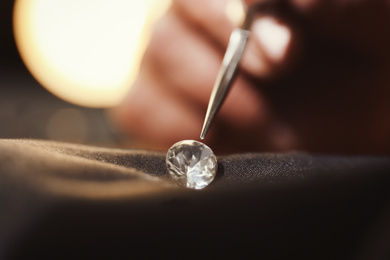 Photo of Professional jeweler evaluating beautiful gemstone, closeup view
