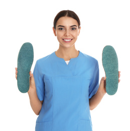 Female orthopedist showing insoles on white background