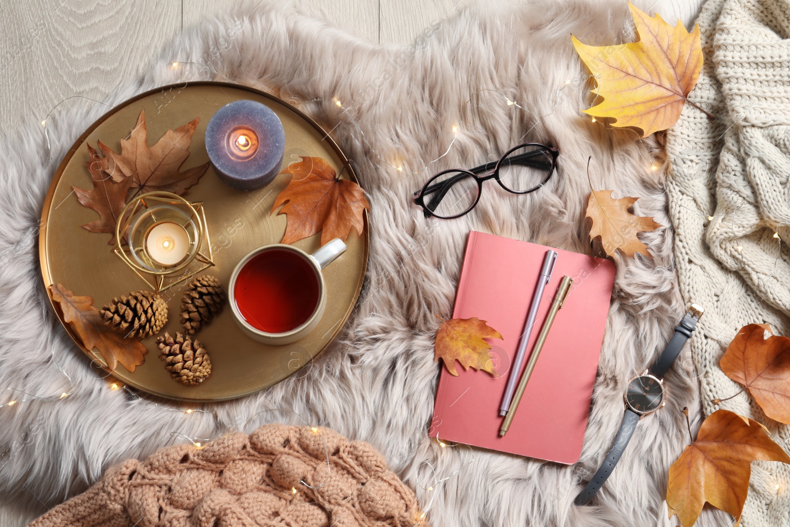 Photo of Flat lay composition with book, cup of tea and warm clothes on fuzzy rug