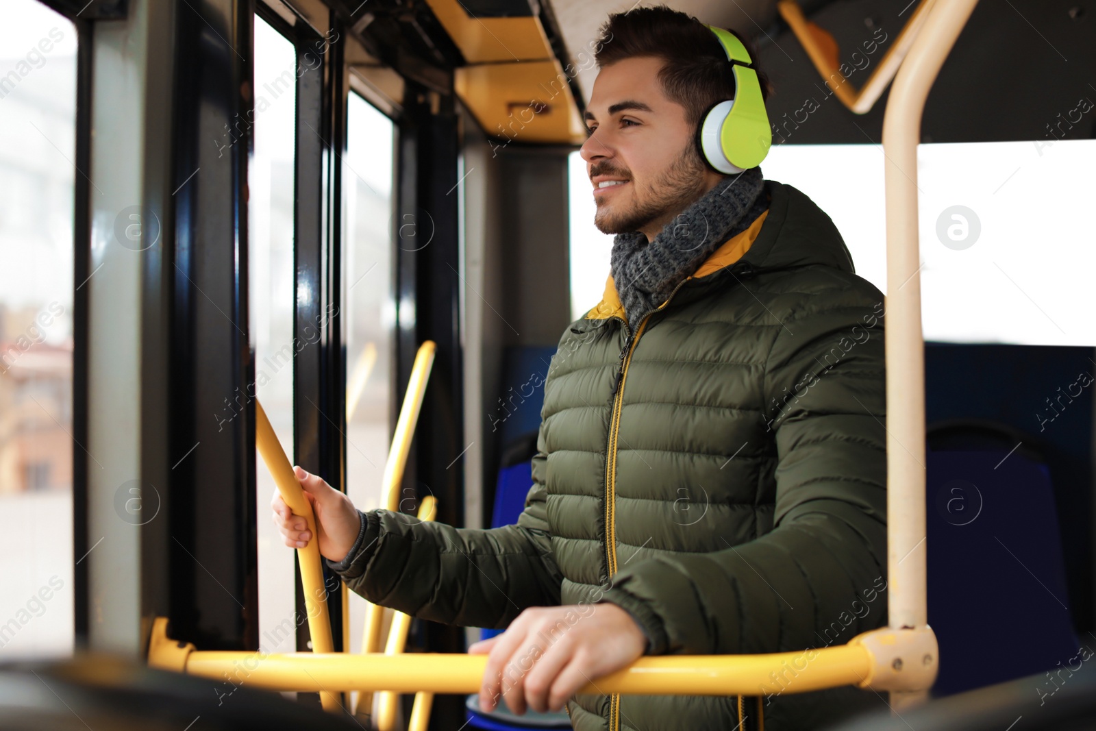 Photo of Young man listening to music with headphones in public transport