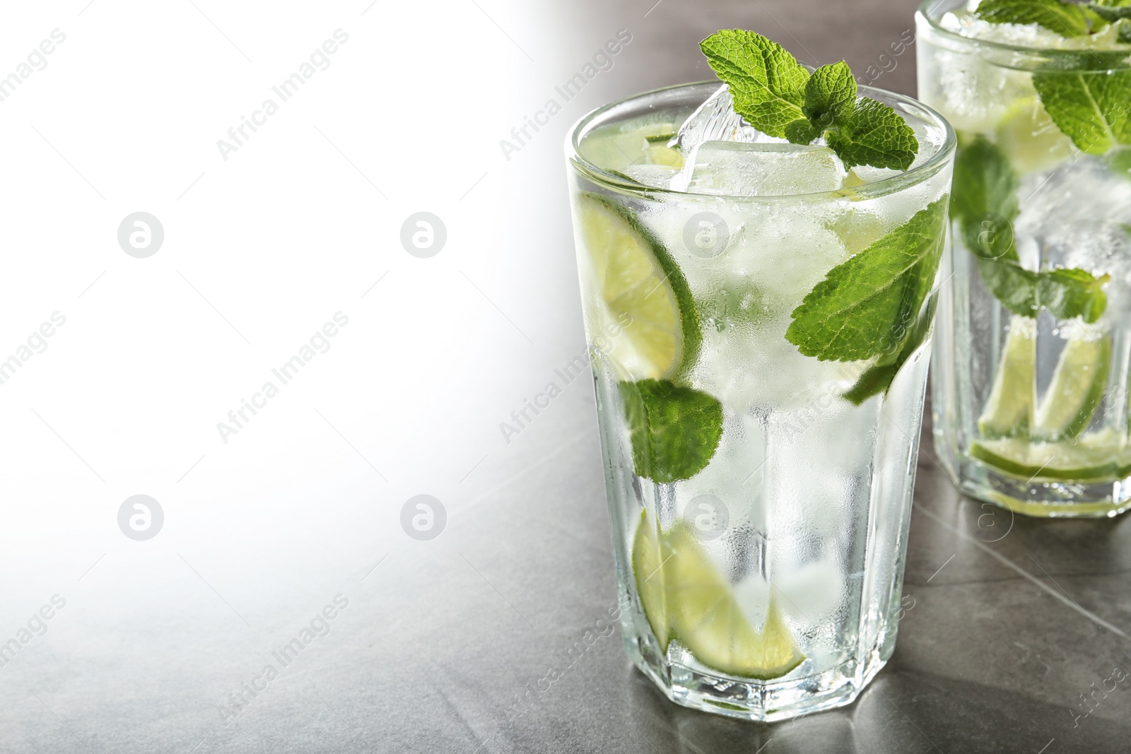 Photo of Tasty Mojito cocktail with ice cubes on light grey table, closeup. Space for text