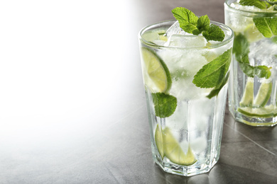 Tasty Mojito cocktail with ice cubes on light grey table, closeup. Space for text