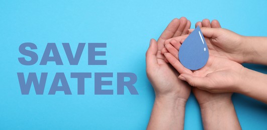 Image of Save Water concept. Man and woman holding paper drop on light blue background, top view