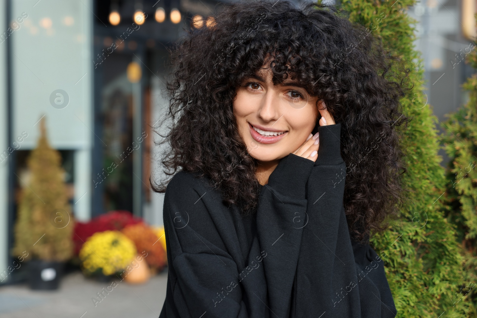 Photo of Happy young woman in stylish black sweater outdoors, space for text