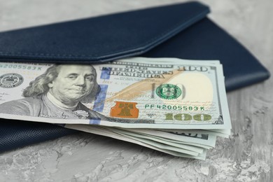 Photo of Money exchange. Wallet with dollar banknotes on grey stone background, closeup