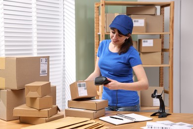 Photo of Parcel packing. Post office worker with scanner reading barcode indoors