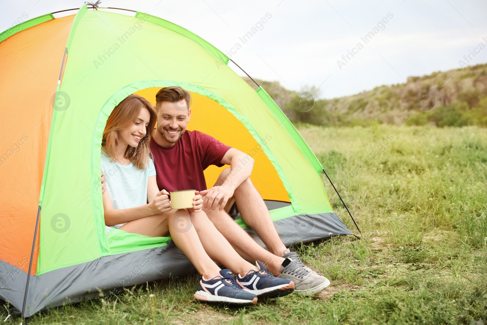 Photo of Young woman with mug and man in camping tent