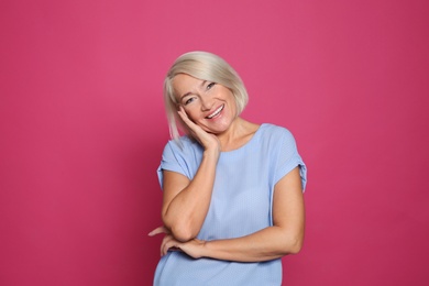 Portrait of mature woman laughing on color background