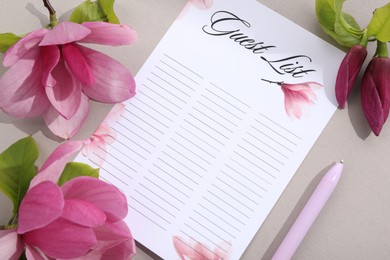 Guest list, pen and beautiful flowers on grey background, flat lay. Space for text