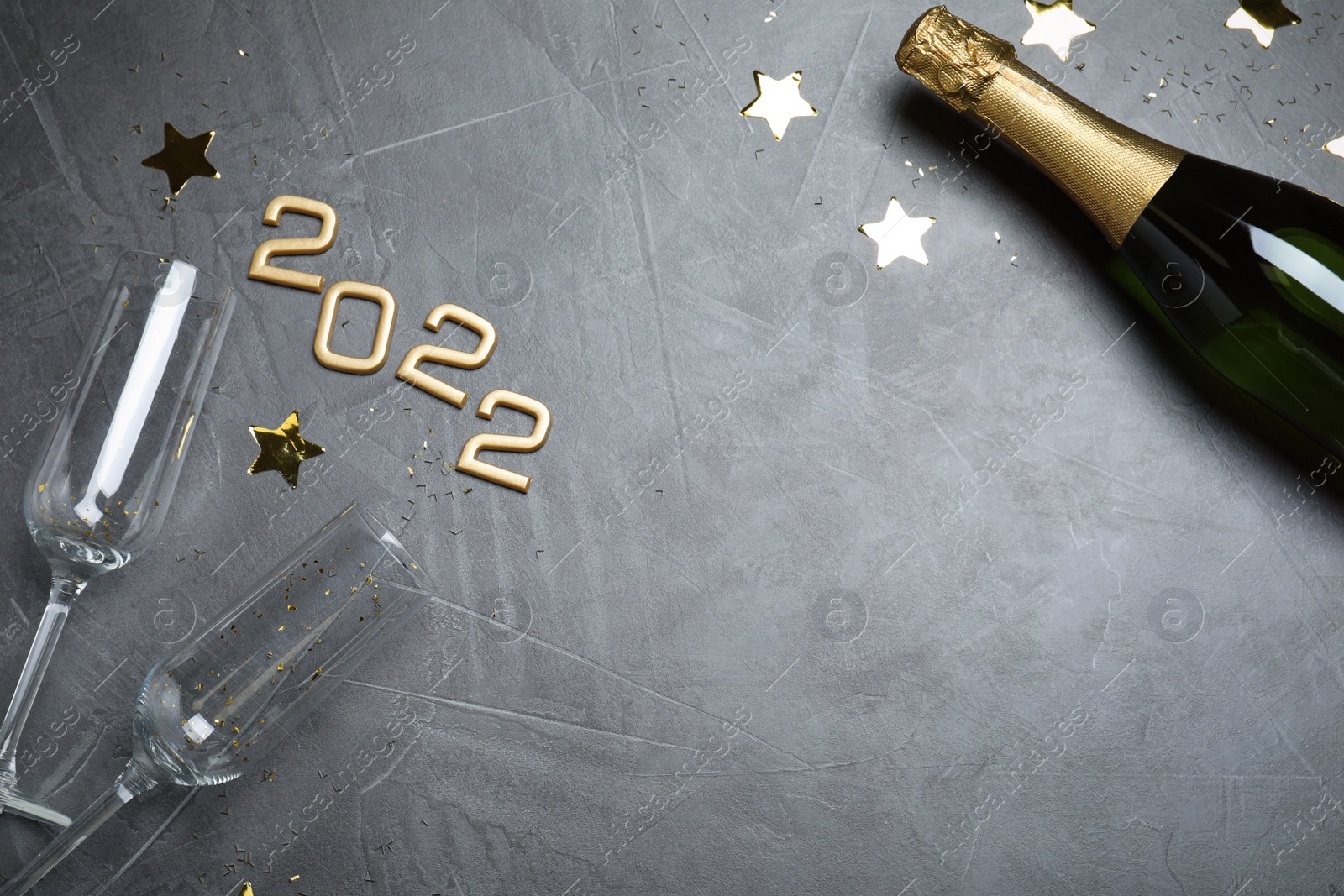 Photo of Happy New Year 2022! Flat lay composition with bottle of sparkling wine on grey table, space for text