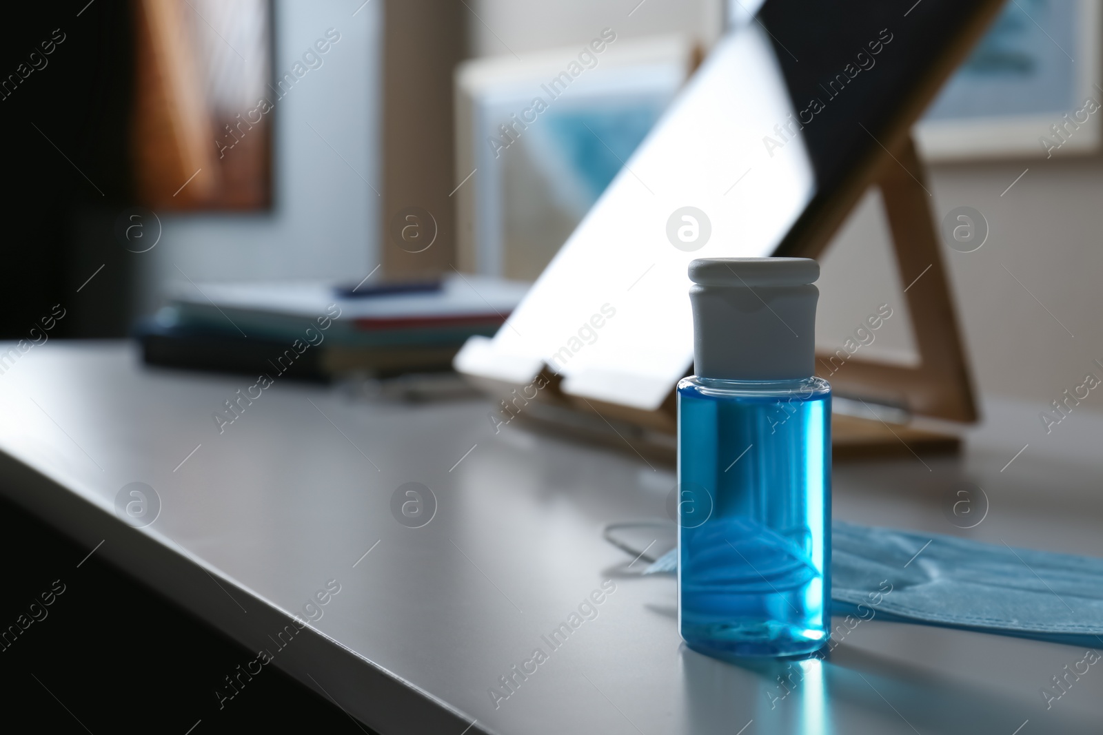 Photo of Hand sanitizer and respiratory mask on table indoors. Protective essentials during COVID-19 pandemic