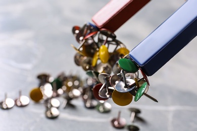 Red and blue horseshoe magnet attracting push pins over table, closeup