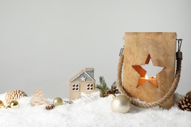 Photo of Composition with wooden Christmas lantern on snow against light grey background, space for text