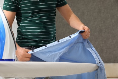 Man ironing shirt on board at home, closeup