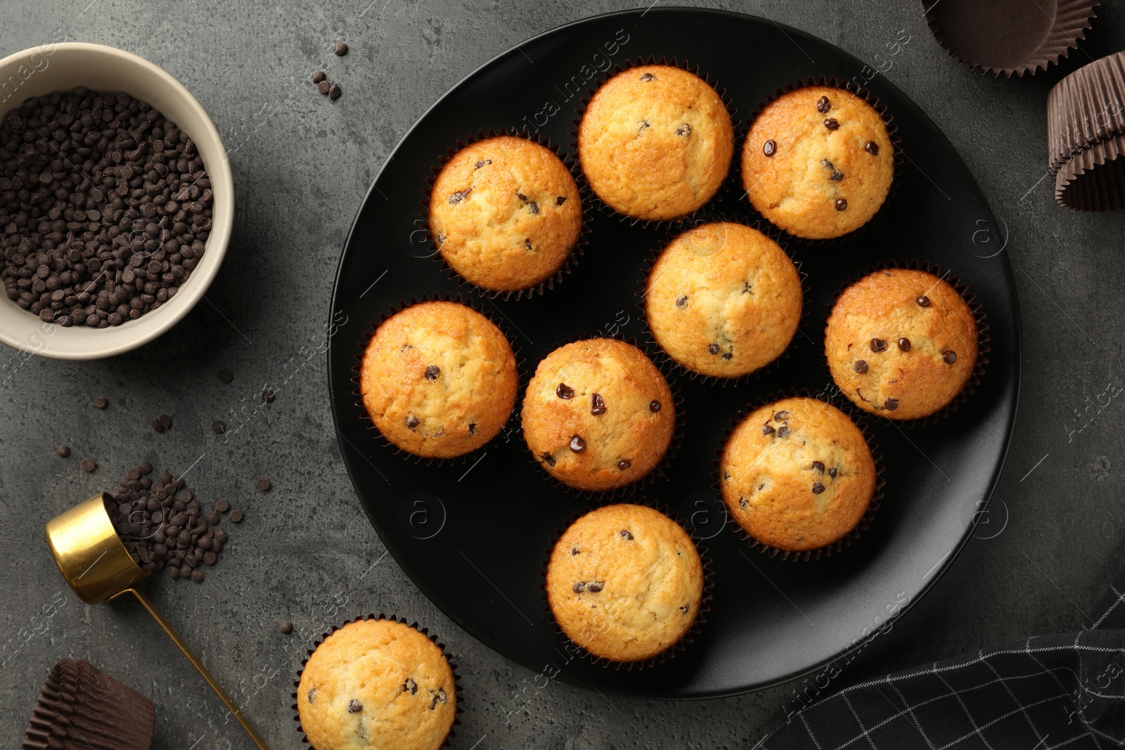 Photo of Delicious freshly baked muffins with chocolate chips on gray table, flat lay