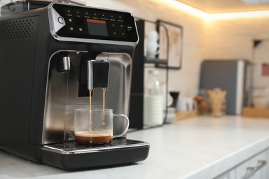 Modern coffee machine making espresso in kitchen, space for text