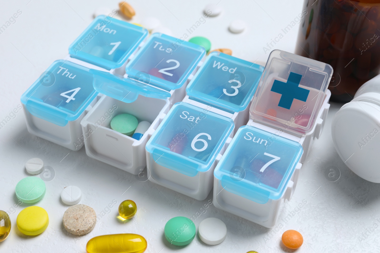 Photo of Weekly pill box with medicaments on white table, closeup