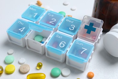 Weekly pill box with medicaments on white table, closeup