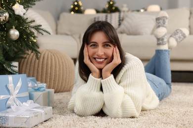 Photo of Portrait of smiling woman with Christmas gifts at home