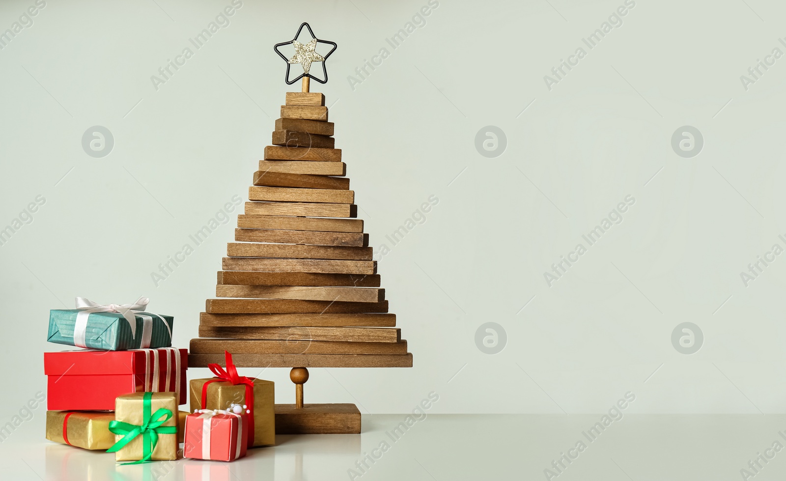 Photo of Decorative wooden Christmas tree with gift boxes on white background