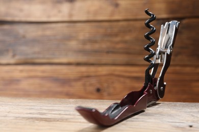Photo of One corkscrew (sommelier knife) on wooden table, closeup. Space for text