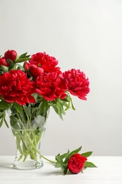 Photo of Vase with beautiful blooming peonies on table against light background