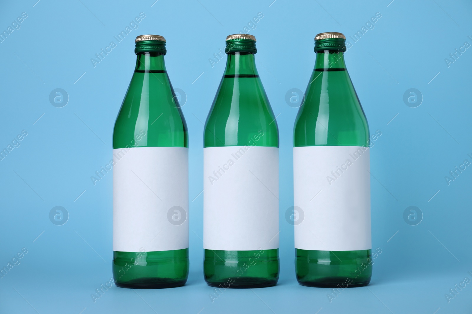 Photo of Glass bottles with soda water on light blue background