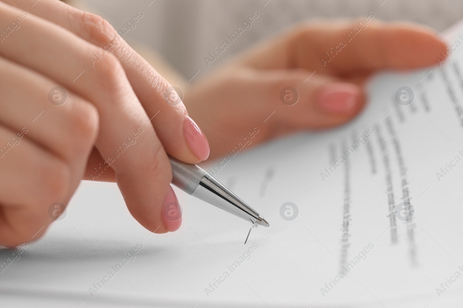 Photo of Woman signing document with pen, closeup view