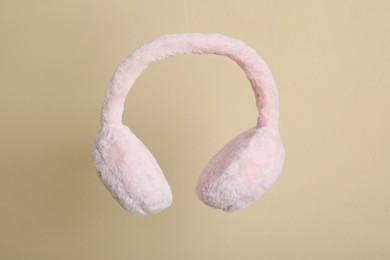 Fluffy earmuffs on beige background. Stylish winter accessory