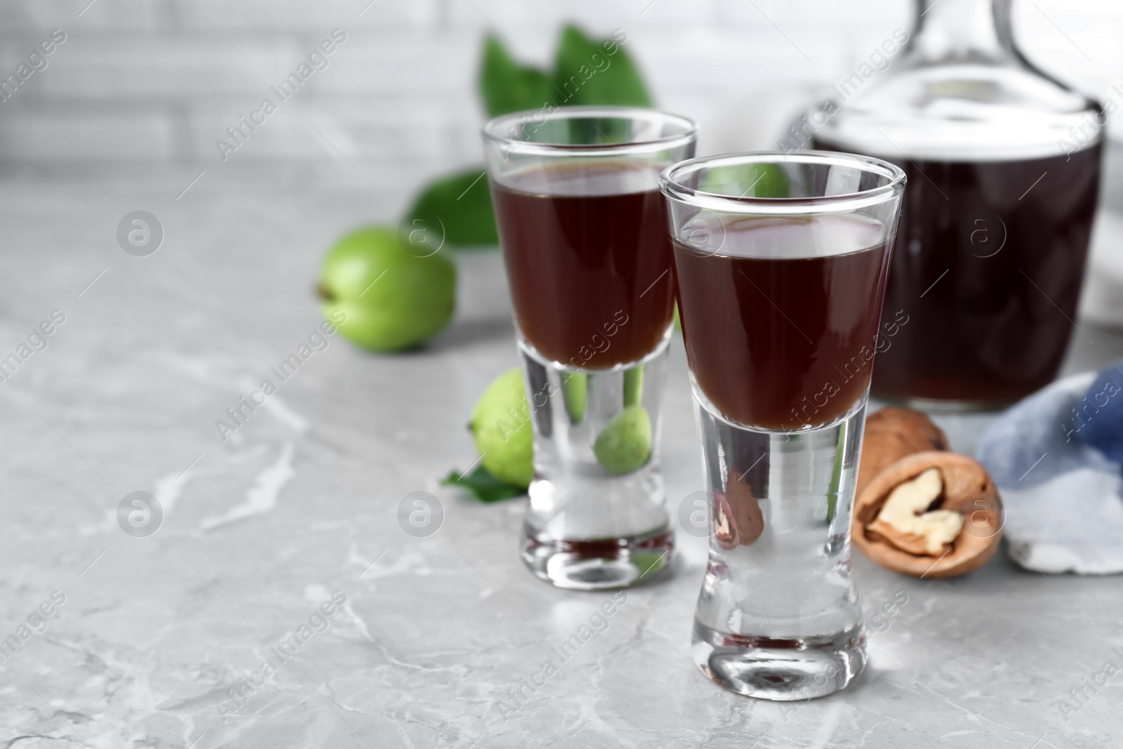 Photo of Delicious liqueur and fresh walnuts on light grey table. Space for text