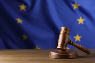 Photo of Judge's gavel on wooden table against European Union flag. Space for text