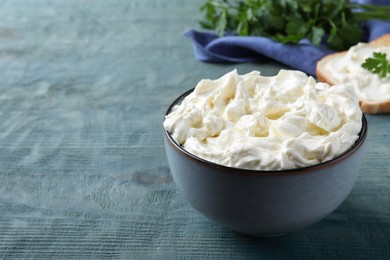 Photo of Tasty cream cheese on light blue wooden table. Space for text