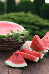 Photo of Tasty ripe watermelon on wooden table outdoors