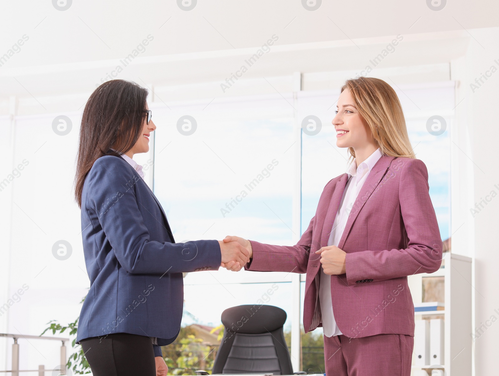 Photo of Human resources manager shaking hands with applicant during job interview in office