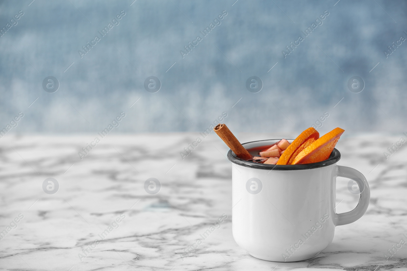Photo of Mug with red mulled wine on marble table. Space for text