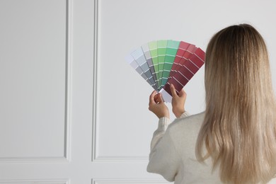 Photo of Woman with paint chips choosing color for wall indoors. Interior design
