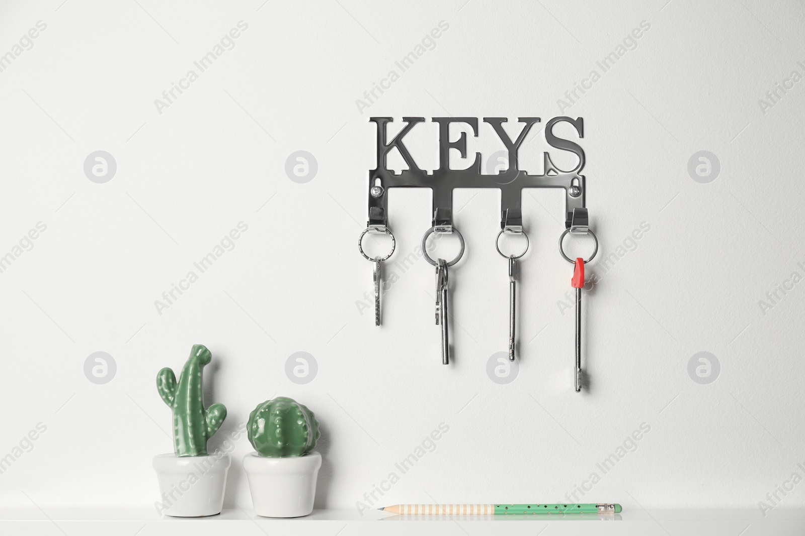 Photo of Metal key holder on light wall indoors