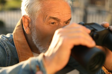 Photo of Concept of private life. Curious senior man with binoculars spying on neighbours outdoors, closeup