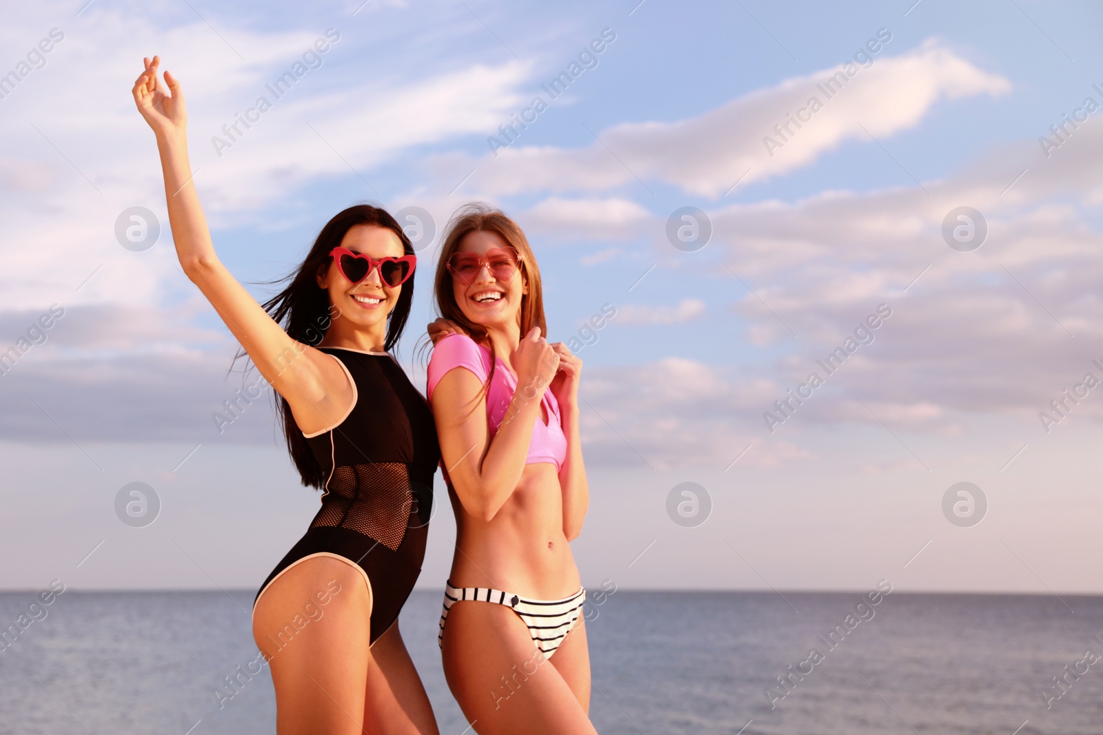 Photo of Young woman in bikini with girlfriend on beach. Lovely couple