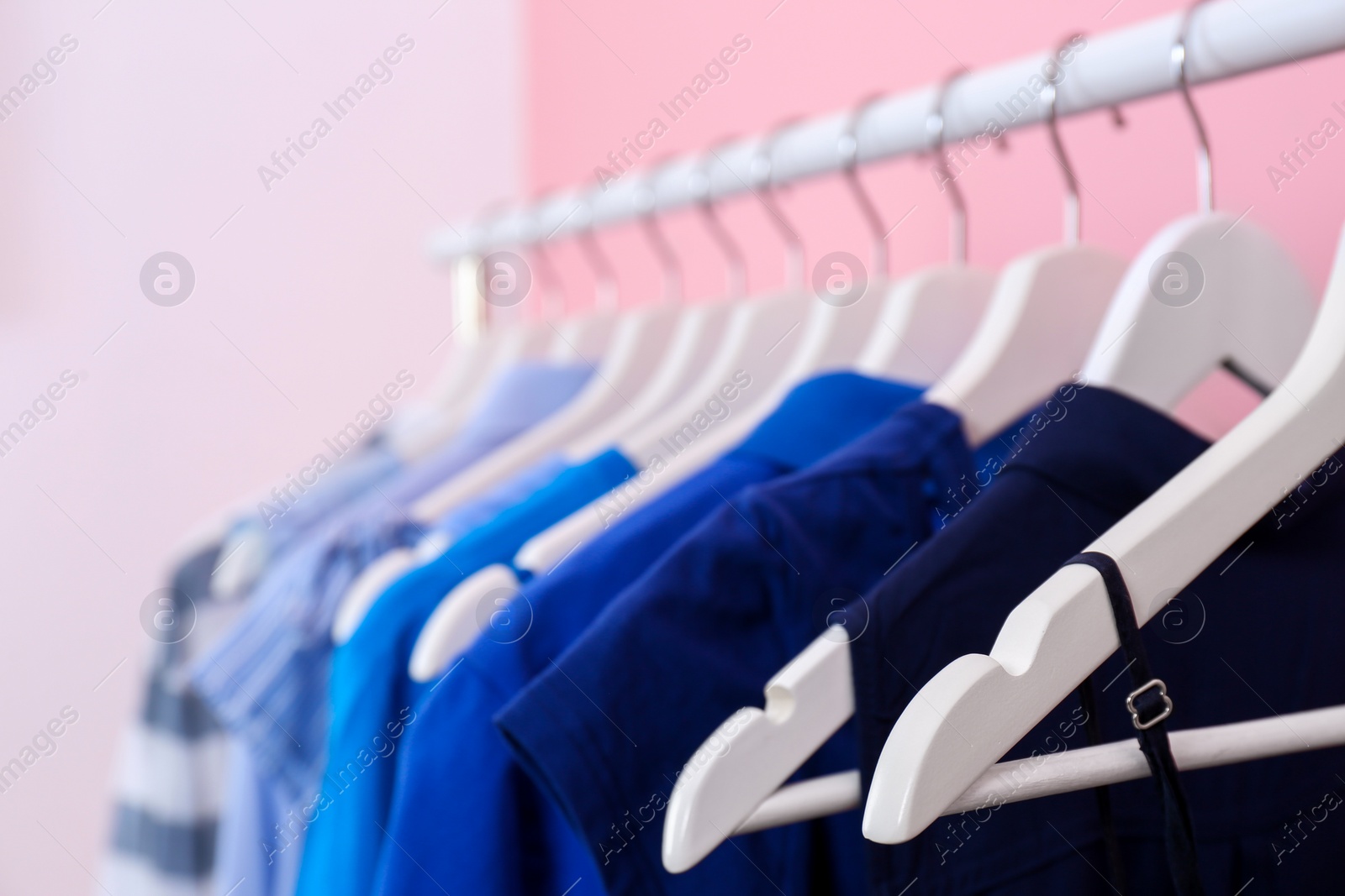 Photo of Bright clothes hanging on rack in room